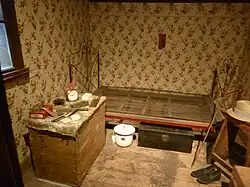 Small bedroom has bedframe with spring and small dresser.