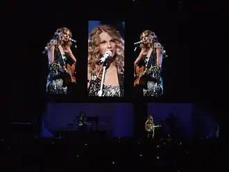 Taylor Swift donning a sparkling cocktail dress and playing a rhinestoned acoustic guitar