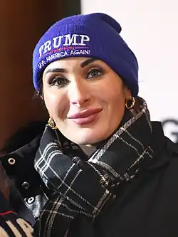 Head shot of Laura Loomer smiling at an event, wearing a MAGA beanie