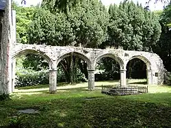 a row of four stone arches in front of trees