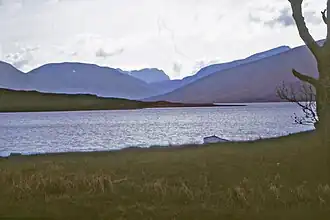 Looking up the loch from near its outflow. The furthest mountain is Slioch, the one on the right overtopping the nearer shoulder is the Fisherfield Munro Mullach Coire Mhic Fhearchair