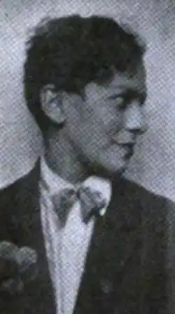 A young Black woman with short hair, wearing a tailored shirt and jacket with a bow tie