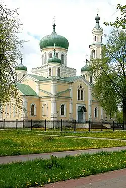 A yellow church with green domes