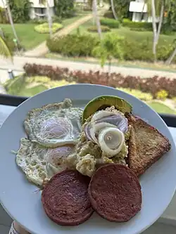 Mangu with salami, fried cheese, fried eggs, onions, and avocado.