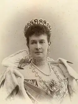 Black and white photo of a woman wearing a tiara and many jewels.
