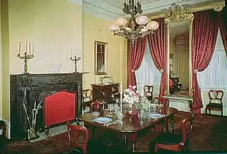 An image of one of the parlors, which has a table at the center and a fireplace on one wall