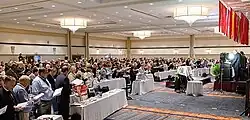 People gathering in a large room for a meeting of the Metropolitan New York Synod of the Evangelical Lutheran Church in America.