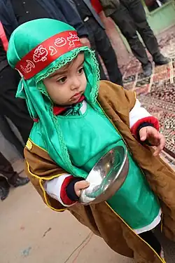 A child in a Shi'ite ritual wearing a red headband with the name "Ruqayyah" written on it
