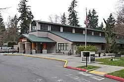 A building with a triangular, green roof and several windows.