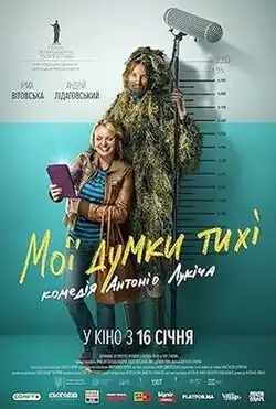 A two metre tall man stands wearing a ghillie suit, holding a boom microphone. A woman stands in front of him, taking a selfie photograph.