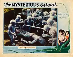 A scene from the film depicting about 14 frog-like humanoids gathered around a lying person in a diving suit. Around the scene, there is an illustration of a fierce white man and a scared white woman with an octopus. There are labels "The MYSTERIOUS Island", "with / LIONEL / BARRYMORE / LLOYD / HUGHES", "A Metro-Goldwyn-Mayer PICTURE", "PHOTOGRAPHED BY TECHNICOLOR PROCESS".