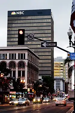 A black, International Style skyscraper with an NBC peacock sign mounted to the top of the facade