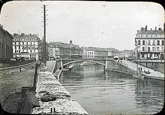 Loading around 1900 of a boat moored at the foot of the Place de la Petite-Hollande [fr] near the Hôtel de La Villestreux [fr]. The Palais de la Bourse is on the opposite bank. The Place du Commerce and Île Feydeau [fr] are connected by the Pont de la Bourse.