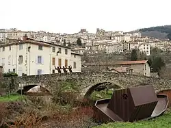 Densely-populated area across a stone arch bridge