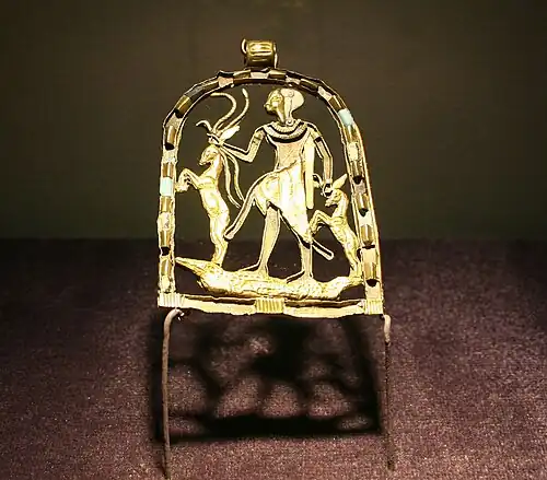 Gold pendant with a figure of a child standing on a crocodile grasping snakes and gazelles