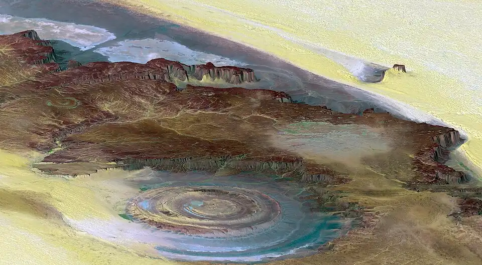 Image 52The Richat Structure is a depression in the country of Mauritania, almost 50 km (30 mi) across. It was originally thought to be the impact of a meteorite. Now it is thought to be a symmetrical uplift (circular anticline or dome) that has been exposed to erosion. In this false-color photo, bedrock is brown, sand is yellow and white, vegetation is green, and salty sediments are blue. (Credit: Landsat 7.) (from Portal:Earth sciences/Selected pictures)