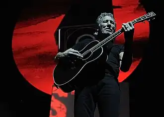 Roger Waters playing guitar in concert