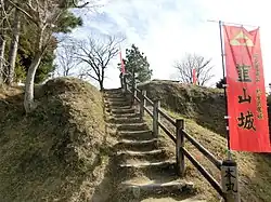 Outdoor steps leading up the side of a grassy mound, with trees in the distance