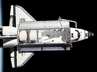 Top view of a spaceplane in space, with the horizon of Earth in the background