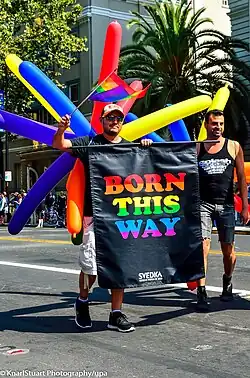 Two man holding a "Born This Way" sign.