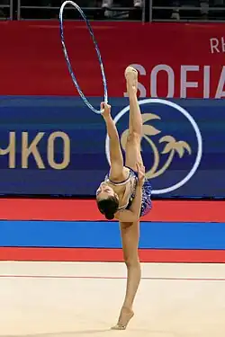 Raffaeli in a side split holding the hoop