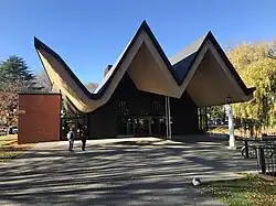 a single level church with a crazy swooping triangle roofline sits amongst trees