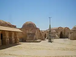 Rocky buildings and an antenna-like structure in a desert.