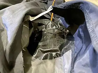 The inner taffeta lining cut open, where the device is aligned to the hole and secured with duct tape.