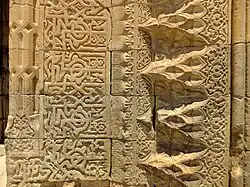 Decoration around the frame of the portal: Kufic calligraphy on the left and muqarnas corniche on the right