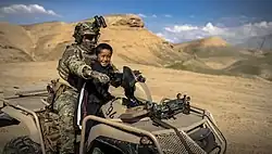 Commando on a Suzuki KingQuad with an Afghan boy near Mazar-e-Sharif.