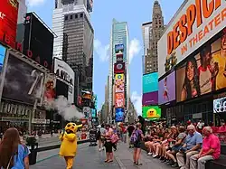 Times square with people sitting on a bench and a costumed character