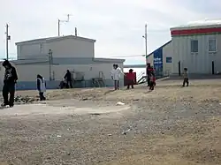 Women carry their children in amautiit while walking to Northern Store, past Isuma productions (left) and the Coop hotel (right)
