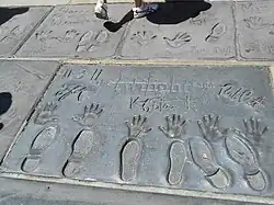 Handprints, footprints and signatures of three adults imprinted into concrete on the ground