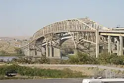 A pair of long bridges crossing a river as seen from the shore