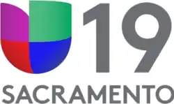 At left, the Univision network logo, consisting of red, purple, green and blue blocks in the shape of a U. At right, a gray number 19 in a sans serif. Beneath is the word "Sacramento".