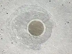 the brass end of Vertical Earth Kilometer sitting flush with the concrete