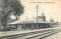 A postcard showing a one-story stone railway station with a small tower