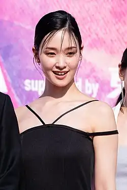 Goriki in black spaghetti strap dress looking toward right of audience