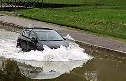 A car is passing through shallow water