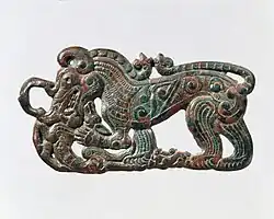 Hebilla de cinturón con forma de lobo en pie, característica de los artefactos nómadas del sur de Ningxia y sudeste de Gansú y relacionado con los estilos escitas de la cultura Pazyryk. s. IV AEC.[17]​[14]​
