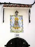Vista de plafón cerámico con la imagen de la Virgen de los Desamparados en la fachada de una casa de Ademuz (Valencia), año 2003 (s/f).