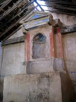 Vista del interior de la ermita de San Pedro en El Cuervo (Teruel), con detalle del presbiterio, altar y retablo.