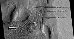 Material que fluye a través del borde de un cráter, visto por HiRISE, bajo el programa HiWish. Las morrenas laterales están etiquetadas.