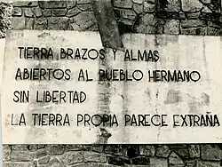 Detalle del monumento con la frase Tierra, brazos y almas abierto al pueblo hermano sin libertad, la tierra propia parece extraña.
