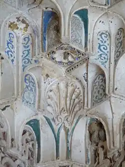 Primer plano de detalles tallados y pintados en los nichos constituyentes de una cúpula de mocárabe en la Sala de los Reyes de la Alhambra