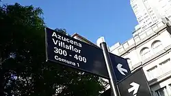 Cartel negro indicativo de la calle Azucena Villaflor, con la aclaración de las alturas "300 - 400" y debajo "Comuna 1"