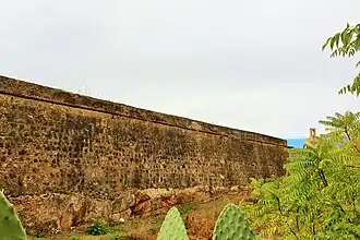 Lienzo al norte elevado sobre roca. Al fondo la Torre de Espantaperros