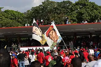 Rostros del presidente venezolano Hugo Chávez y la figura histórica Simón Bolívar durante el funeral del primero (2013): Chávez había creado la revolución bolivariana, un movimiento socialista y nacionalista relacionado al Socialismo del siglo XXI que buscaba una transformación post-soviética de la izquierda.