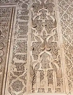 Motivos arabescos y piñas junto con inscripciones caligráficas alrededor del mihrab de la Madrasa de Ben Youssef, en Marrakech (siglo&nbsp;XVI)