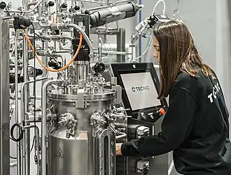 Una mujer trabajando con un biorreactor en una planta piloto